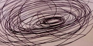 Uno scarabocchio nero e confuso tracciato a matita su un foglio bianco, simbolo di pensieri aggrovigliati.